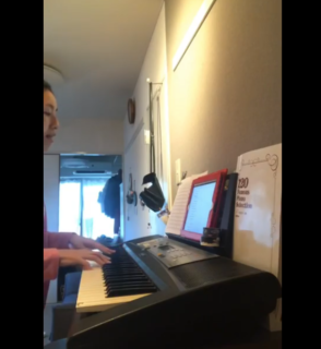 家の中で電子ピアノでスーパーバタードッグのサヨナラcolorを弾いている女性